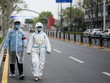 Dân Vũ Hán mặc đồ bảo hộ đi trên phố ngày 31/3. Ảnh: AFP.