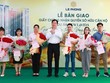 Đại diện Tập đoàn Lê Phong trao giấy chứng nhận quyền sở hữu căn hộ và hoa cho cư dân.