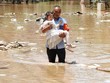 Sơ tán trẻ em khỏi khu vực bị ngập do mưa lũ. (Ảnh: AFP/TTXVN).
