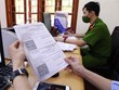 Giấy đi đường có mã nhận diện được lực lượng công an phường Văn Quán, quận Hà Đông đối chiếu và xét duyệt để cấp cho các cá nhân và doanh nghiệp thực hiện dịch vụ công ích thiết yếu trên địa bàn. (Ảnh: Phạm Kiên/TTXVN).