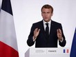 Tổng thống Pháp Emmanuel Macron bên cạnh quốc kỳ Pháp đã có thay đổi màu lam sáng thành lam đậm (Ảnh: AP).
