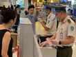 Nhân viên an ninh hàng không được trang bị đầy đủ găng tay, khẩu trang, tấm chắn giọt bắn trong khi đo thân nhiệt cho hành khách.