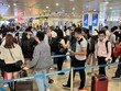 Hành khách xếp hàng dài chờ vào khu vực kiểm tra giấy tờ tùy thân và soi chiếu an ninh tại sân bay Nội Bài. (Ảnh: CTV/Vietnam+).