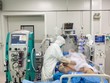 Bác sĩ bệnh viện Chợ Rẫy khám cho bệnh nhân H.C.C khi còn nguy kịch, phải chạy ECMO nhưng từ ngày 6/7, bệnh nhân đã tỉnh táo hơn. Dù bệnh nhân vẫn còn phải thở oxy dòng cao do phổi còn hạn chế vì thể trạng béo phì, tuy nhiên tình trạng sức khỏe đang cải thiện dần (Ảnh: Bệnh viện Chợ Rẫy).
