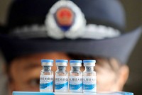 Cán bộ hành pháp Trung Quốc đưa một lô vắcxin đi kiểm tra. Ảnh: EPA.