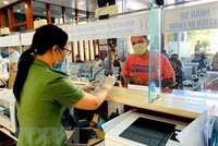 Cán bộ Công an cửa khẩu Tân Sơn Nhất chủ động trang bị đầy đủ khẩu trang, găng tay trong khi làm nhiệm vụ. (Ảnh: Thành Chung/TTXVN).