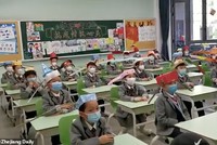 Bằng cách đội mũ giãn cách một mét, cách em học sinh tiểu học sẽ hạn chế tiếp xúc gần nhau.  