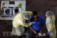 Nhân viên y tế lấy mẫu dịch xét nghiệm COVID-19 cho người dân tại Singapore ngày 10/6/2020. (Nguồn: AFP/TTXVN).