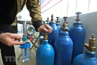 Thành viên Tổ hỗ trợ theo dõi người nhiễm COVID-19 tại nhà phường Lĩnh Nam kiểm tra bình oxy trước khi mang đến hỗ trợ F0 cách ly y tế, điều trị tại nhà. (Ảnh: Minh Quyết/TTXVN).