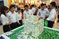 Nhân viên môi giới bất động sản giới thiệu dự án với 
khách hàng tại một hội chợ bất động sản diễn ra tại Hà Nội. Ảnh: Dũng Minh