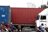 Bị xe container bịt kín lối đi, người dân phải luồn lách trước bánh xe “hung thần” để về nhà. Ảnh: Việt Dũng