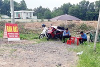 Nhân viên môi giới ngồi chơi dài chờ khách bên cạnh một dự án lớn