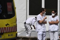 Hai nhân viên y tế trò chuyện cạnh xe cứu thương bên ngoài bệnh viện La Paz ở Madrid hôm 23/3. Ảnh: AFP.