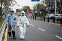 Dân Vũ Hán mặc đồ bảo hộ đi trên phố ngày 31/3. Ảnh: AFP.