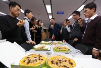 Cán bộ Bộ Chiến lược và Tài chính Hàn Quốc thưởng thức pizza do Tổng thống Moon Jae-in tặng. Ảnh: Yonhap