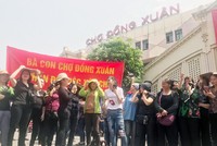 Nhiều tiểu thương căng băng rôn phản đối xây chợ sáng 9/4. Ảnh: Giang Huy.