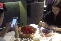 Nhân viên ngồi bóc vỏ tôm càng trong khi thực khách dùng điện thoại di động. (Nguồn: Handout)