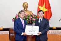 Thứ trưởng Lê Hoài Trung (phải) trao số tiền ủng hộ thông qua đại sứ Lào tại Việt Nam Thongsavanh Phomvihane. Ảnh: Bộ Ngoại giao.