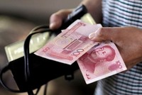 Người mua hàng cầm tờ 100 NDT tại một khu chợ ở Bắc Kinh. Ảnh: Reuters.