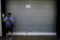 Một người qua đường đứng trước cửa tiệm dán thông báo đóng cửa vì biểu tình ở Hong Kong hôm 5/8. Ảnh: Reuters.