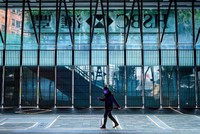 Một người đeo khẩu trang đi bộ trước Ngân hàng HSBC tại Hong Kong. Ảnh: CNN.