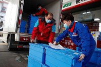 Công nhân trạm xăng của Sinopec tại Bắc Kinh bốc dỡ các thùng rau củ quả ngày 28/2. Đây là dịch vụ mới của Sinopec, gọi là đặt mua thực phẩm "không chạm" mùa dịch. Ảnh: Reuters.