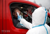 Nhân viên y tế kiểm tra thân nhiệt một lái xe tại khu vực cửa khẩu Jedrzychowice giữa Đức và Ba Lan. (Ảnh: AFP/TTXVN).