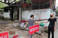 Người thân chuyển nhu yếu phẩm cho người trong khu vực cách ly ngõ 165 Cầu Giấy. (Ảnh: Thành Đạt/TTXVN).