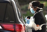Nhân viên y tế lấy mẫu tại một điểm xét nghiệm thiết lập trong bãi đỗ xe ở Chessington, Anh hôm 28/3. Ảnh: AFP.