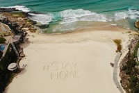 Lời kêu gọi ở nhà để tuân thủ quy định giãn cách xã hội được viết trên một bãi biển ở Sydney. Nguồn Getty.