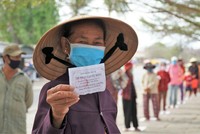 Bà Trần Thị Đảnh, 65 tuổi, cầm phiếu, đứng đầu hàng chuẩn bị vào bấm máy nhận gạo trước trụ sở phường Mũi Né.