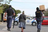 Cảnh sát Nam Phi mang hàng hóa cho một cụ già trên đường đi chợ về. (Ảnh: TTXVN phát).
