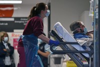 Nhân viên y tế chuyển bệnh nhân nhiễm COVID-19 tới bệnh viện ở London, Anh. (Ảnh: AFP/TTXVN).