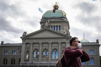 Du khách đeo khẩu trang đi ngang qua Tòa nhà Quốc hội Thụy Sĩ. (Nguồn: AFP).