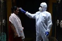 Một bác sĩ kiểm tra thân nhiệt cho người dân tại nơi cư trú ở thành phố Chennai, Ấn Độ, hôm 29/6. Ảnh: AFP.