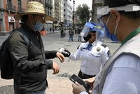 Cảnh sát và nhân viên y tế kiểm tra thân nhiệt của một người qua đường tại thủ đô Mexico City, Mexico hôm 6/7. Ảnh: AFP.