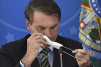 Tổng thống Jair Bolsonaro tháo khẩu trang trong cuộc họp báo. Ảnh: AP.