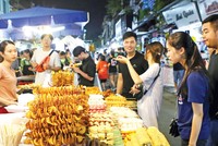 Du khách chọn món ăn tại chợ đêm khu phố cổ (quận Hoàn Kiếm, Hà Nội). Ảnh: Hồ Hạ.