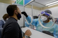 Nhân viên y tế lấy mẫu xét nghiệm Covid-19 cho một người đàn ông ở Sân bay Quốc tế Tocumen, Panama City, thủ đô của Panama hôm 12/10. Ảnh: AFP.