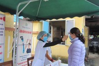 Cán bộ Trung tâm Y tế thành phố Yên Bái kiểm tra thân nhiệt cho bệnh nhân đến khám tại đơn vị (Ảnh: KT).