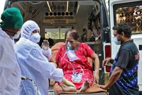 Nhân viên y tế và người thân bế một phụ nữ từ xe cấp cứu đến cơ sở điều trị Covid-19, ở Mumbai, Ấn Độ. Ảnh: Reuters.