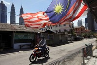 Một người đàn ông đeo khẩu trang lái xe máy trên đường phố Kuala Lumpur, Malaysia ngày 2/2/2021. Ảnh: Reuters.