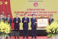 Lãnh đạo huyện Bình Xuyên (bên trái) nhận quyết định và Bằng xếp hạng di tích quốc gia đặc biệt Cụm đình Hương Canh. (Ảnh: Hoàng Hùng/TTXVN).