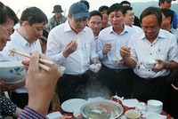 Ông Huỳnh Đức Thơ (người đội mũ) đã trực tiếp chế biến và thưởng thức hải sản của ngư dân ngay tại cảng cá. Ảnh: Đ.X.