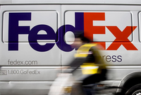 Một chiếc xe đạp lướt quaxe tải giao hàng FedEx đang đỗ tại khuMidtown,New York.Ảnh: Bloomberg.