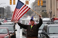 Người đàn ông cầm cờ Mỹ biểu tình phản đối phong tỏa vì Covid-19 tại thành phố Lansing, bang Michigan, hồi tháng 4. Ảnh: AP.