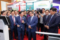 Thủ tướng Chính phủ Phạm Minh Chính thăm và lắng nghe ông Hoàng Minh Ngọc, Phó tổng giám đốc Agribank giới thiệu về hoạt động số của Agribank.