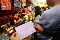 Khách hàng cầm trên tay giấy hẹn lấy vàng ngày vía Thần Tài tại một cửa hiệu vàng trên phố Trần Nhân Tông