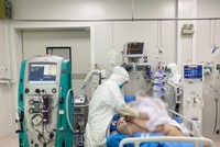 Bác sĩ bệnh viện Chợ Rẫy khám cho bệnh nhân H.C.C khi còn nguy kịch, phải chạy ECMO nhưng từ ngày 6/7, bệnh nhân đã tỉnh táo hơn. Dù bệnh nhân vẫn còn phải thở oxy dòng cao do phổi còn hạn chế vì thể trạng béo phì, tuy nhiên tình trạng sức khỏe đang cải thiện dần (Ảnh: Bệnh viện Chợ Rẫy).