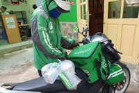 Một tài xế GrabFood bịt khẩu trang khi đi giao hàng.Ảnh: Vietnamnet